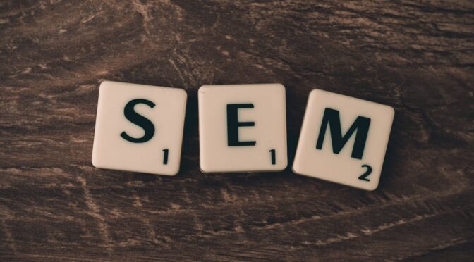 Three Scrabble tiles spelling SEM on a wooden surface, representing search engine marketing.